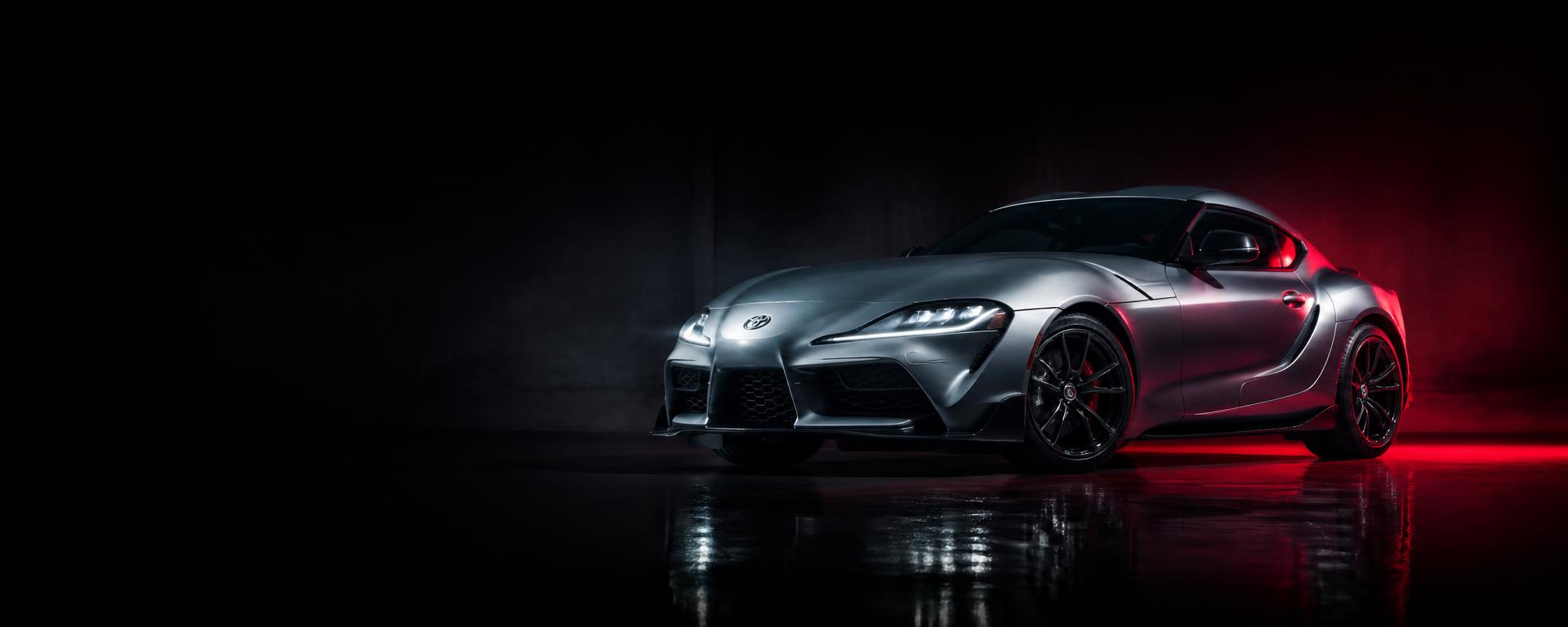 Sports coupe lit with red rim lighting in a dark studio